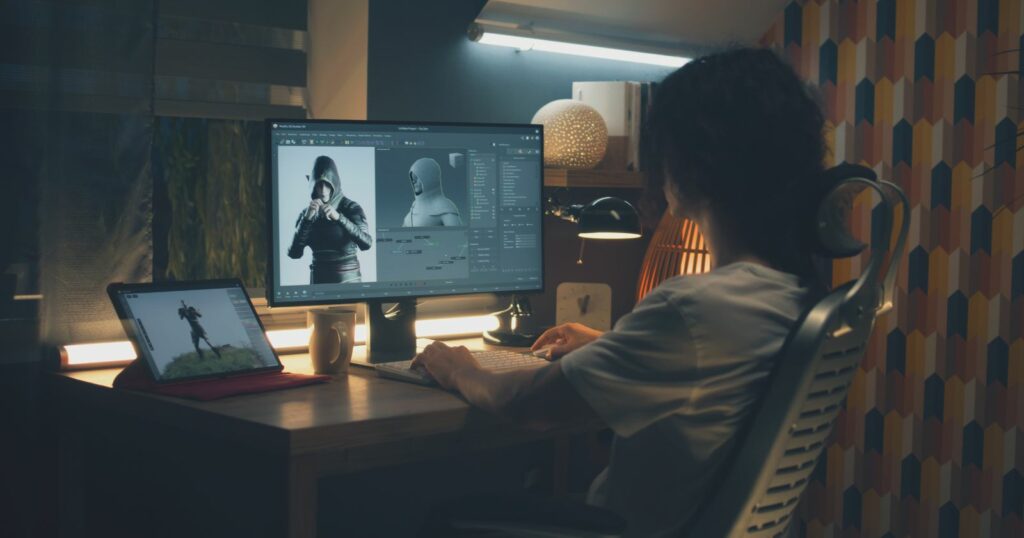 A 3D animator sitting at a desk, focused on a computer screen.