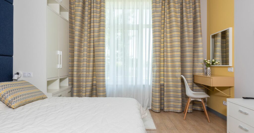 An elegant bedroom with yellow and blue curtains, creating a vibrant and stylish ambiance."