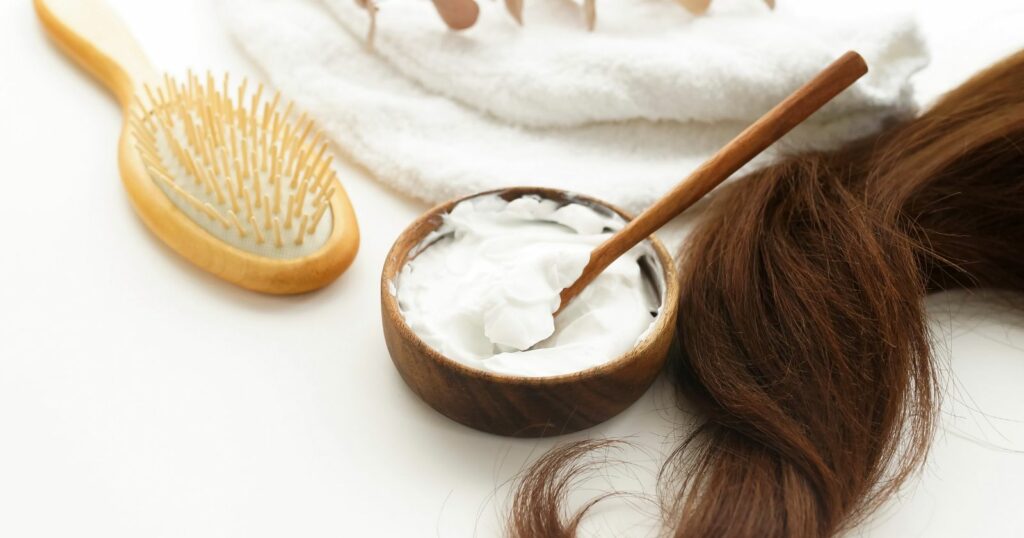 Woman's hair on towel with brush and hair care products for natural hair care.