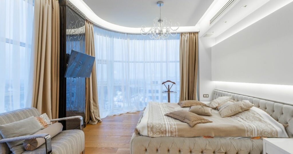 A modern bedroom with a spacious bed and a large window, showcasing stylish furniture.