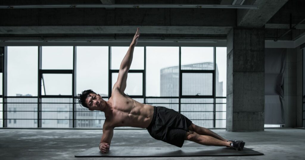 A man performing push ups on a yoga mat in an empty room.