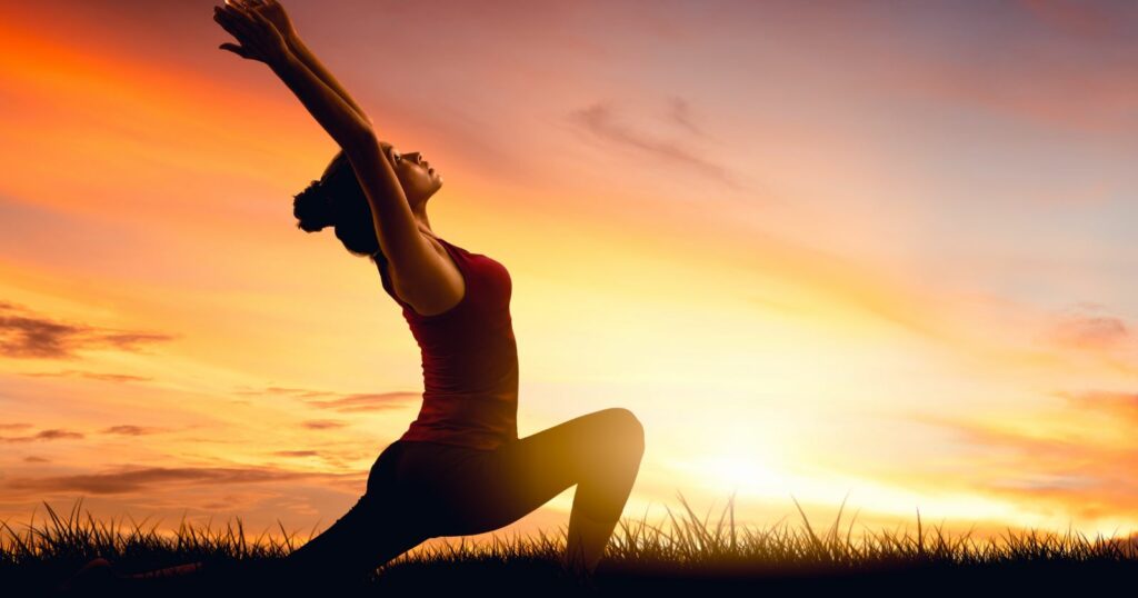 A woman gracefully practicing yoga poses during a serene sunset.