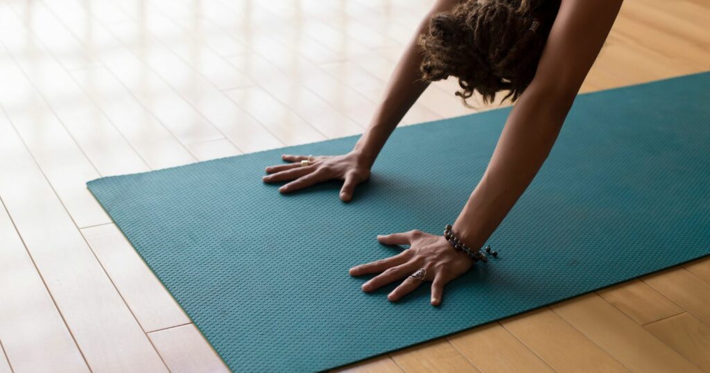 Woman practicing yoga on blue mat with yoga equipment.