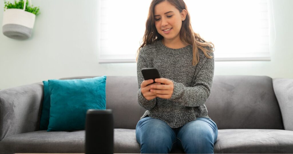 Woman on couch with smart speaker, Bluetooth enabled.