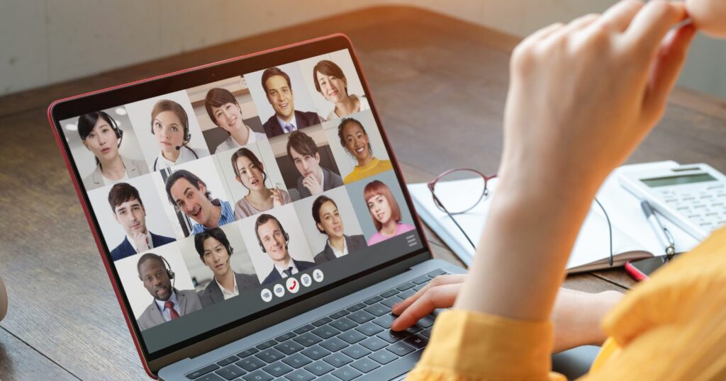 A woman working remotely at a call center, using a laptop with a video chat displayed on the screen.