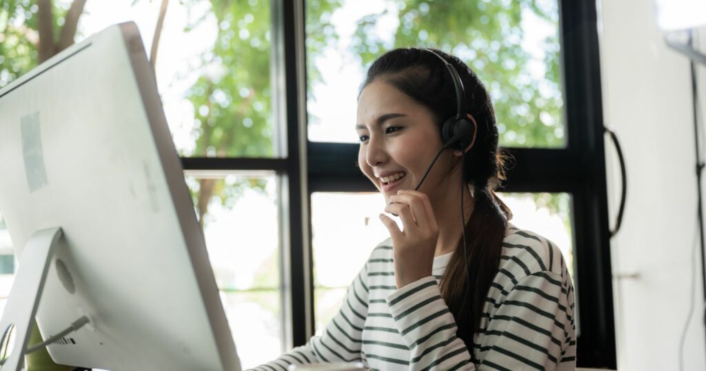 Woman in headset working at computer for call center remote work.