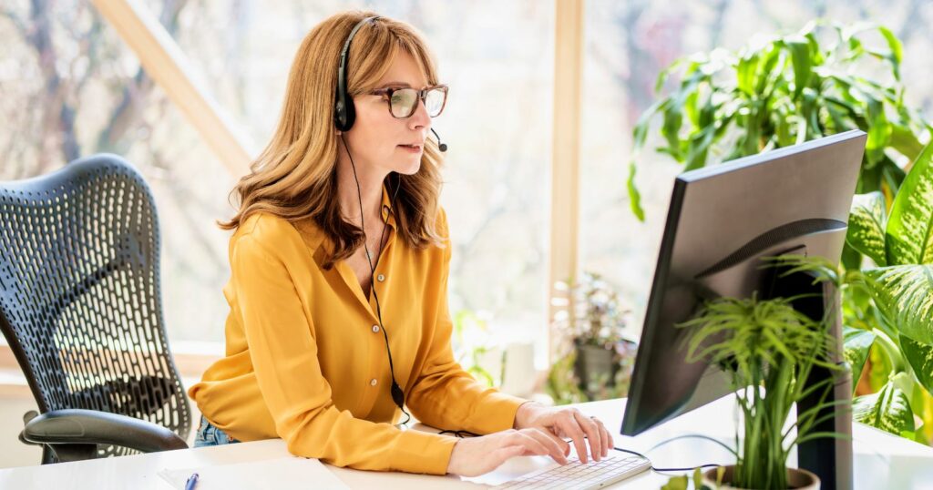 Woman in headset working at computer for call center remote work.