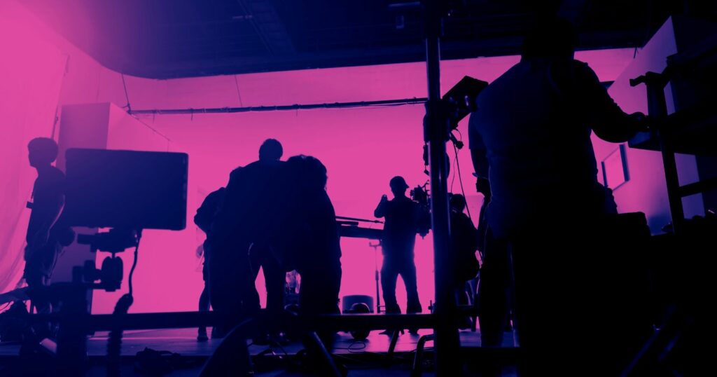 Purple-lit studio with production team.