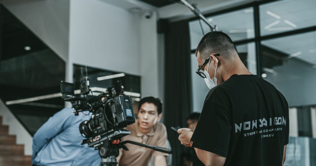 A man filming a video in a room with a production team.