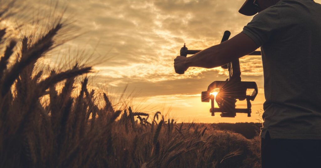 A man capturing the essence of nature with a camera in a field, showcasing his skills in cinematography.