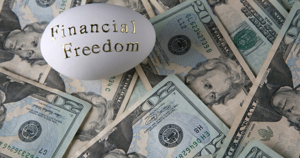 Egg with financial freedom written in gold around dollars symbolizing financial freedom.