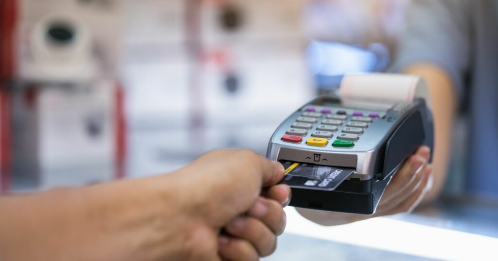 A person securely pays at a cash register using a credit card, ensuring the safety of their transaction.