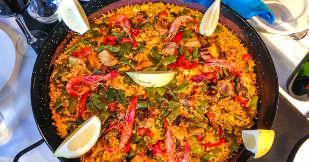 A delicious Spanish paella, served on a table with a knife and fork, ready to be enjoyed.