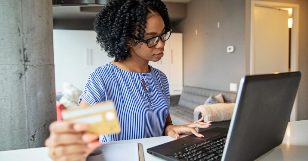A woman at home, using her laptop and credit card to navigate the application process.