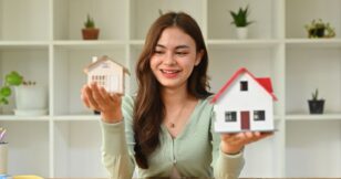 Asian woman proudly holds up a house model, symbolizing the future of home loans. Exciting possibilities await!
