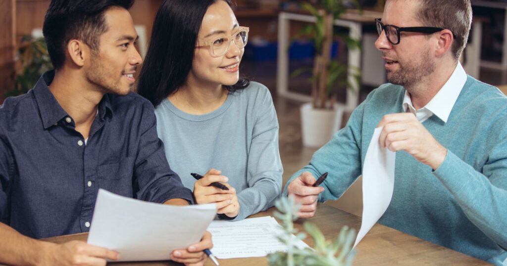 Three individuals discussing papers at a table, while focusing on understanding home equity loan.