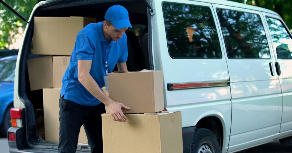 A man in a blue shirt and hat loading boxes into a van, diversifying services to meet market demand.