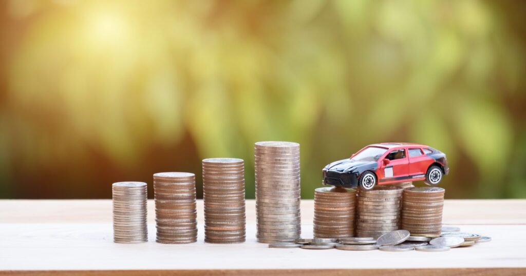 Car atop coins on a green background, representing savings with car insurance companies.