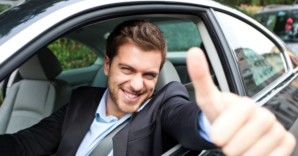 A man in a car giving the thumbs up, showcasing Innovations in Car Insurance.