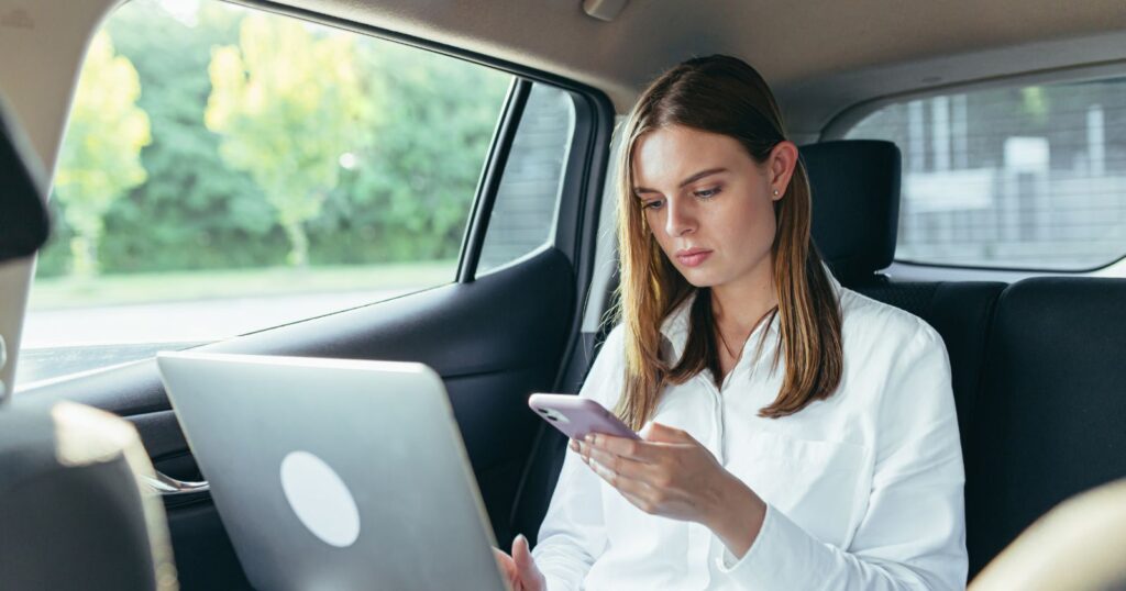 A woman engrossed in her cell phone while sitting in the back seat of a car. Maximizing Social Media Engagement.