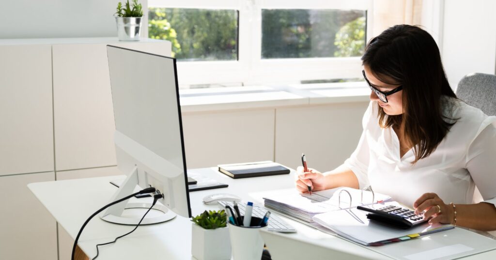 A woman focused on her computer screen, diligently researching bank offers at her desk.