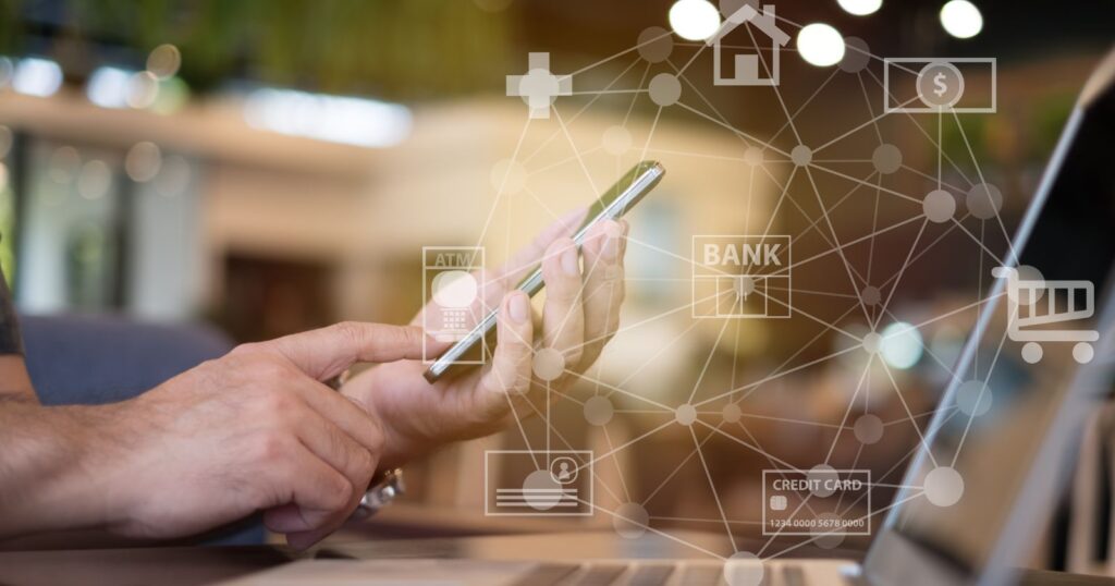 A man multitasking with a smartphone and laptop, surrounded by internet icons. Illustrating the 2024 Landscape of Checking Account Bonuses.