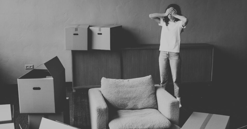 A woman stands in a room surrounded by boxes.