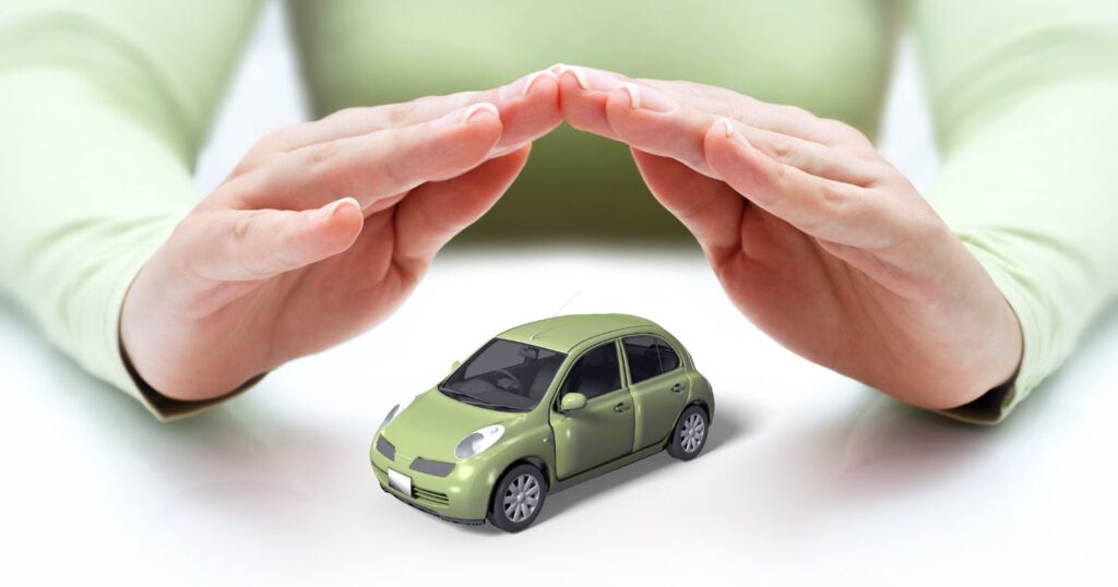 Person demonstrating a small green car being held up with their hands, representing insurance coverage options.