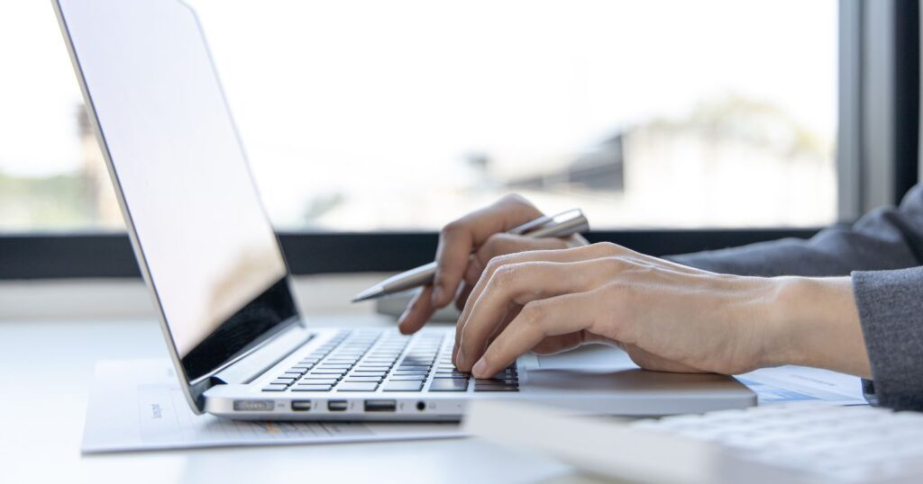 A person typing on a laptop computer, using online calculators for efficient and accurate calculations.