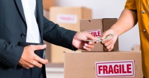 A man in casual attire giving money to a person in a suit, illustrating the etiquette of tipping movers.