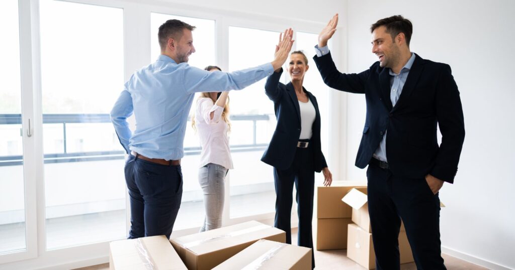 Business people celebrating success in an empty room, symbolizing achievement and teamwork in 'The Future of Office Relocations'.