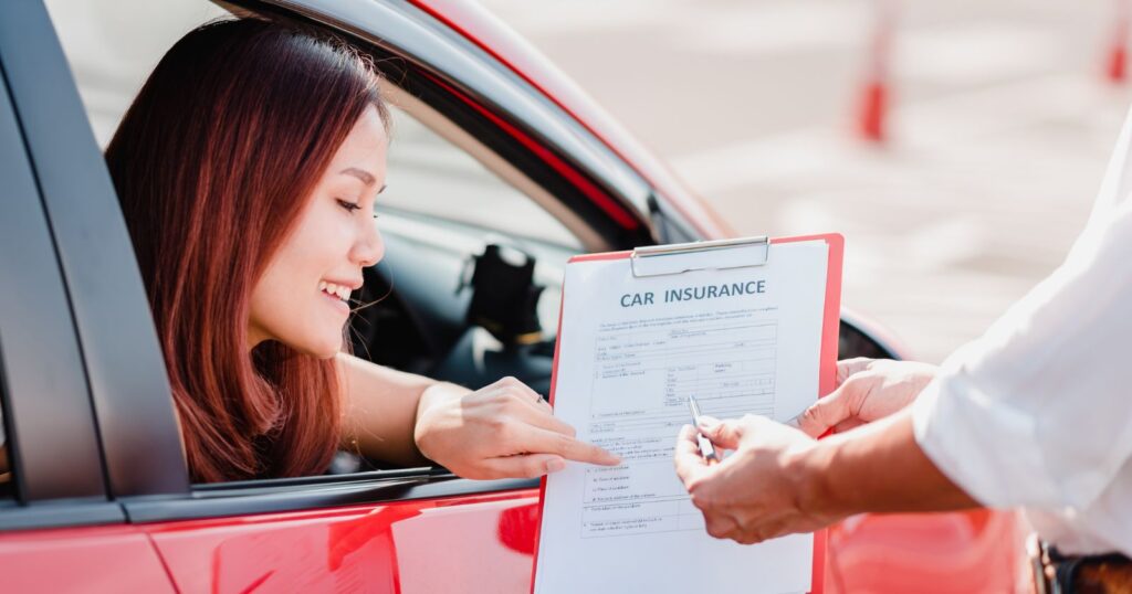 A woman signing a car insurance document. The image depicts the impact of coverage type on monthly costs.