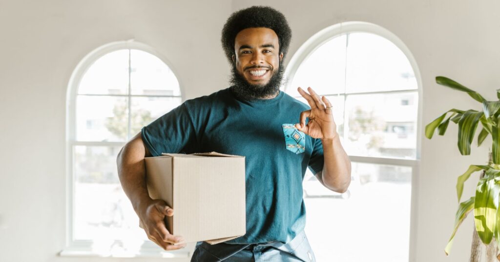 A man happily holds a box, signifying a successful move.