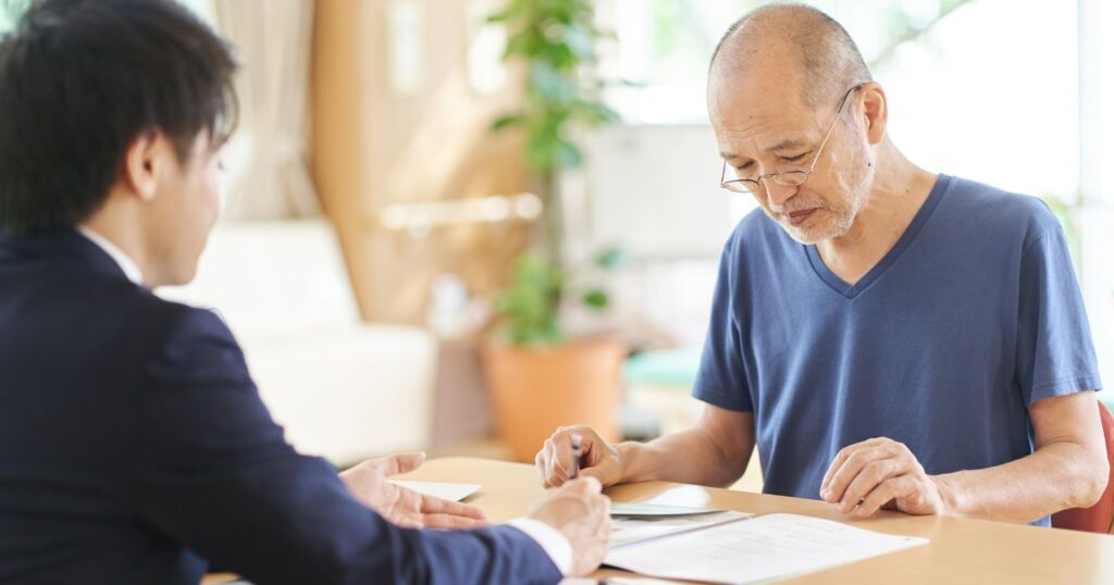 An older man and a younger man sitting at a table, discussing long-term care insurance options.