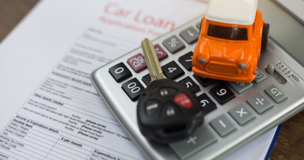 Image of car loan calculator and keys on paper, with text "How to Calculate Your Car Insurance".