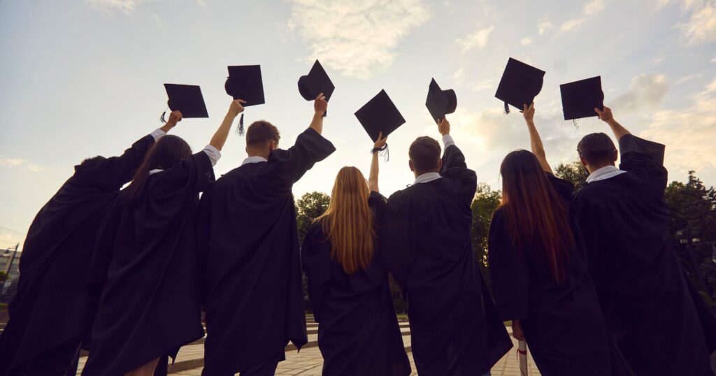 Graduates in caps and gowns, holding their caps. Symbolic representation of accomplishment and success in higher education.