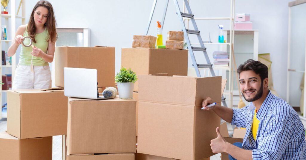 A couple moving boxes in a room. Image related to understanding tipping etiquette for movers and packers.